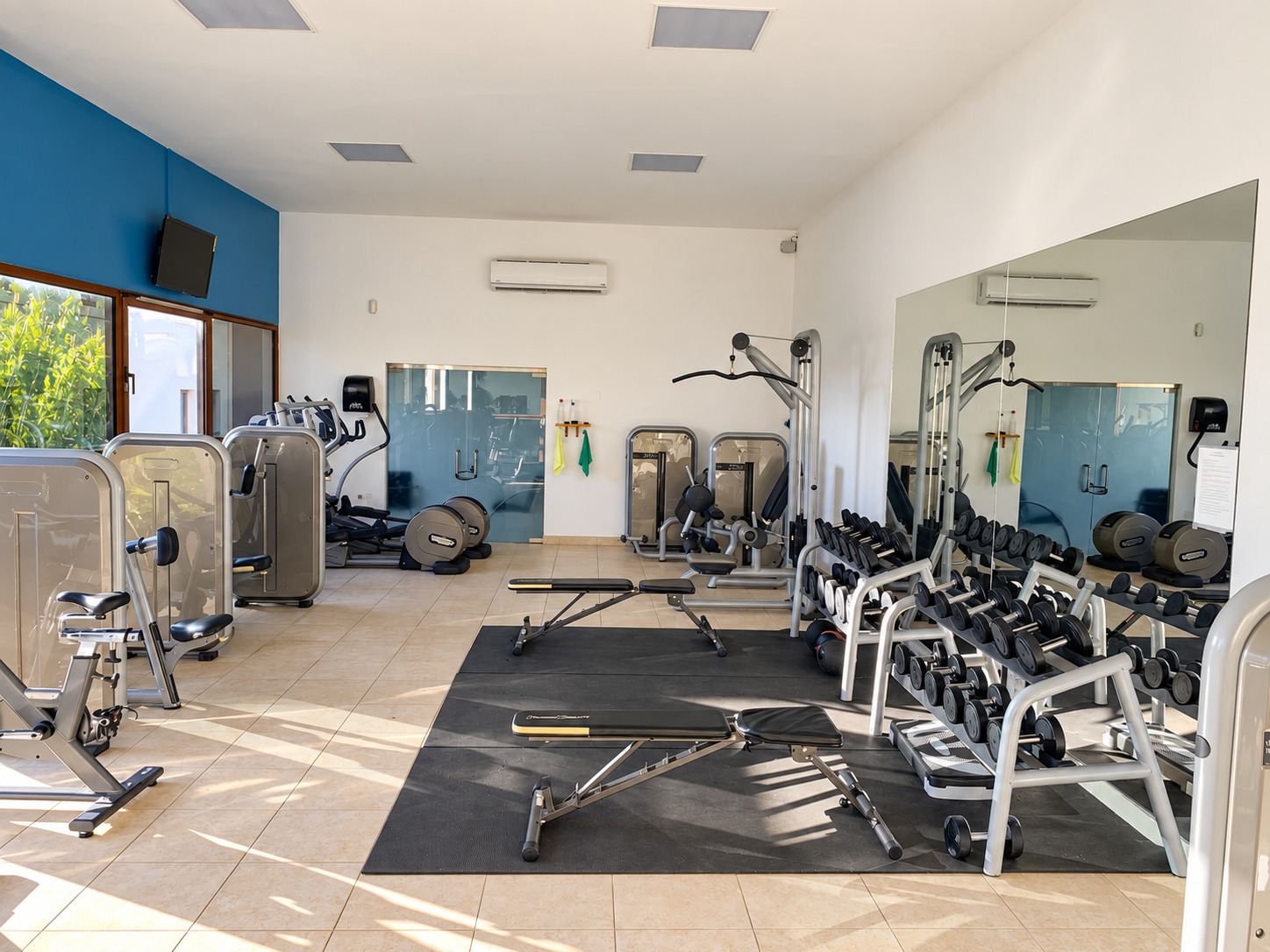 Porto Cupecoy gym with free weights, benches, strength machines and a mirrored wall.