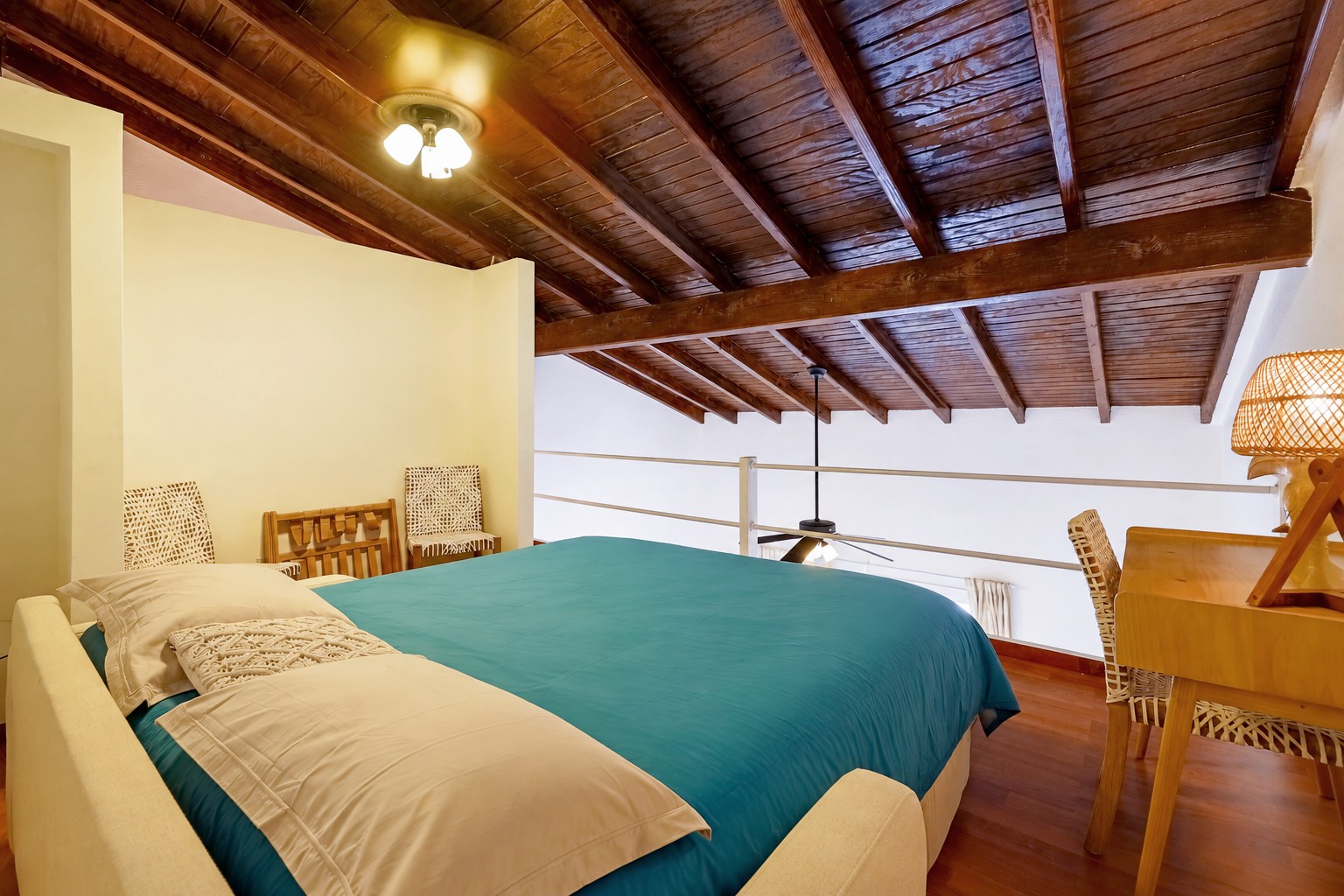 Loft sleeping area beneath the wooden ceiling, with a Queen sofa-bed beside the railing overlooking the living area.