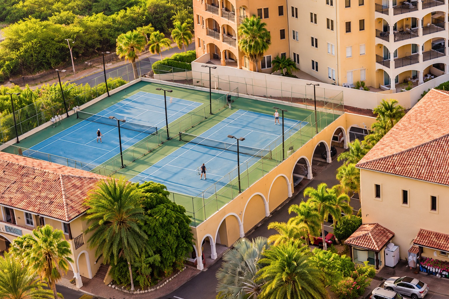 Two tennis courts with floodlight poles, surrounded by greenery at Porto Cupecoy.